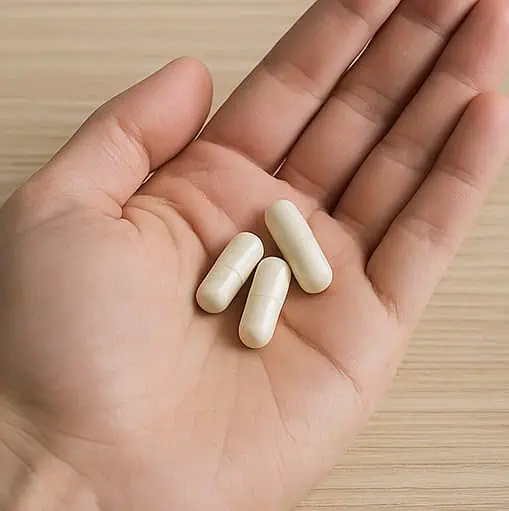A picture of three capsules resting on a person's palm.